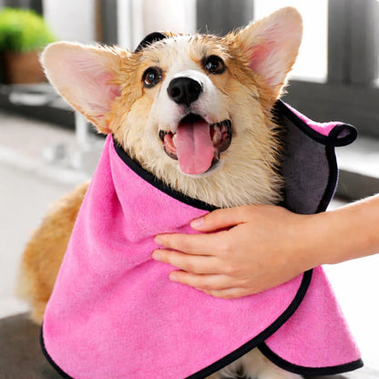 Chien mouillé enveloppé dans une serviette rose absorbante à séchage rapide après le bain
