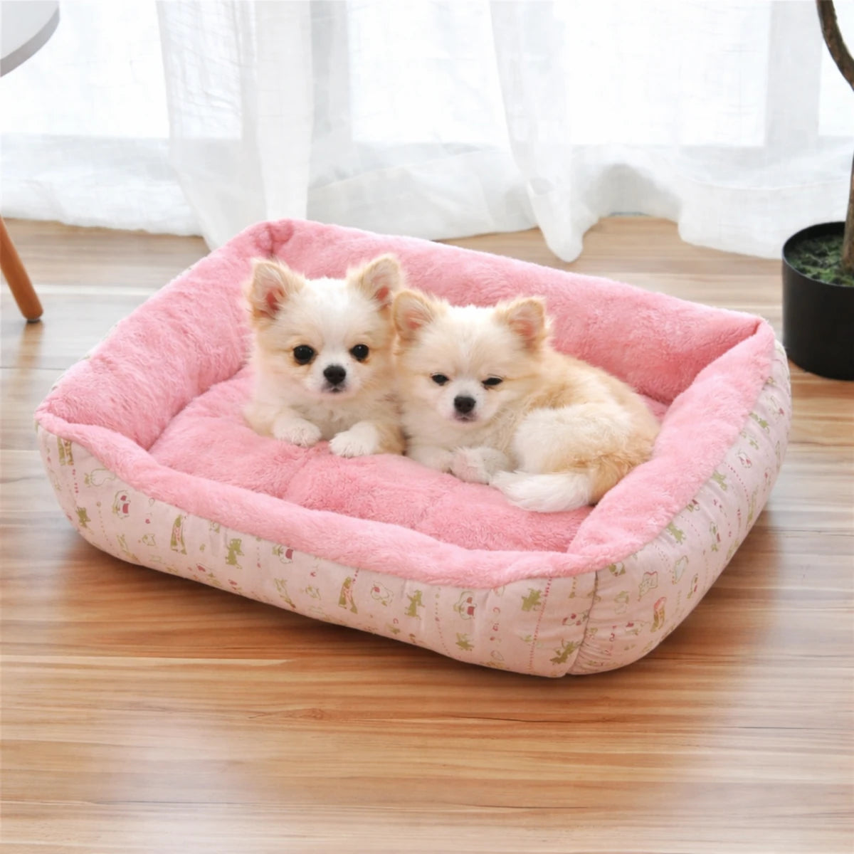 Deux chiots allongés dans un panier pour chien rose moelleux